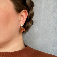 Varpu -malliston pieni ruskea korvakoru henkilön päällä jolla ruskea paita.