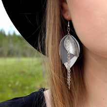 Kaima Designin Bloom-malliston isot valkoharmaat korvakorut, käsintehty poronnahasta, lähikuva koruista mallin päällä.