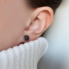 Kaima Designin Kelo-sarjan musta pieni nappikorvakoru mallin korvassa, lähikuva.